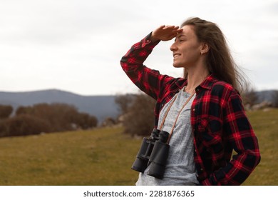 Young woman looking out over the horizon with binoculars hanging on her neck