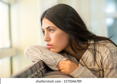 Young Woman Looking Out The Window In Deep Thought.