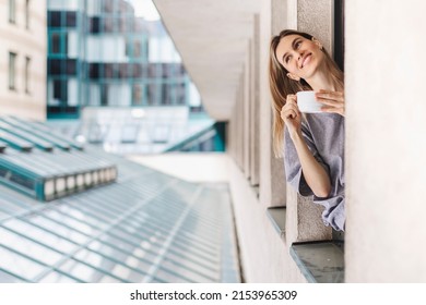 Young Woman Looking Out The Window And Holding Mug At Home Or Hotel Room. She Drinking Coffee Or Tea After Wake Up In The Morning. Good Morning! Woman Look Happy, Positive Mood, Sitting On Windowsill.