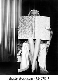 Young Woman Looking Over Top Of An Oversized Book