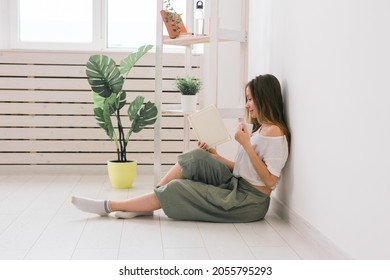 Young Woman Looking Photo Album At Home And Drink Tea. Memories And Leisure Concept.