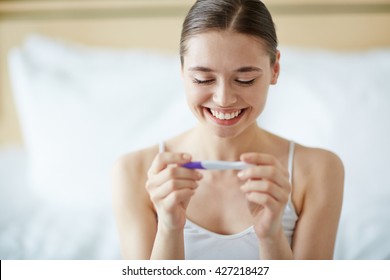 Young woman looking at pregnance test in happiness