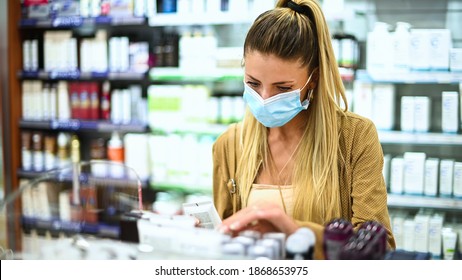 Junge Frau, die in einem Laden nach einem Produkt sucht, das eine Koronavirus-Maske trägt