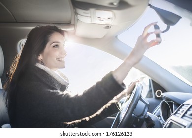 Young Woman Looking In The Rearview Mirror Of A Car