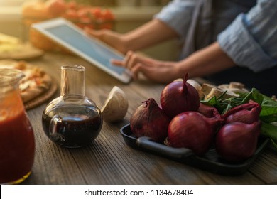 The young woman looking recipe in a tablet computer in kitchen. Healthy food. Healthy lifestyle. Cooking at home. Cooking according to recipe on tablet screen. Technology concept. Toned image. - Shutterstock ID 1134678404