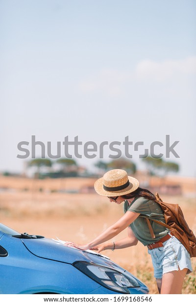 Young woman looking for the\
right way during traveling by car. Tourist girl in Tuscany on\
vacation