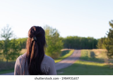 Young Woman Looking Up The Road Ahead Of Her At Sunset