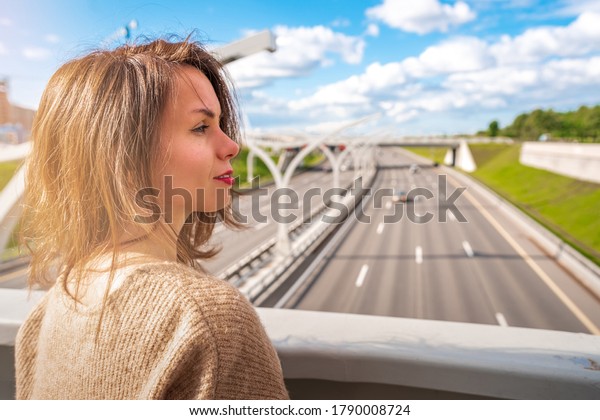  Young woman looking\
at a road section of St. Petersburg Western high-speed diameter in\
the sunlight