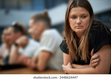 Young woman looking sad, anxious and depressed, introverting and feeling lonely, while in a group of friends. Mental health image, portrayed by an actress.