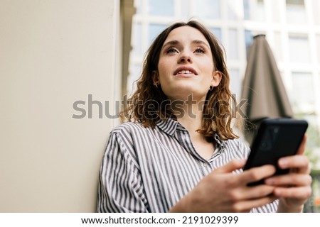 Young woman looking to the side with cell phone in hand