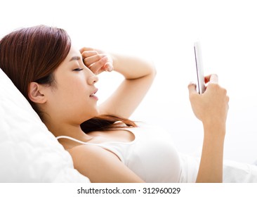 Young Woman Looking Smart Phone With Tired Eyes On The Bed