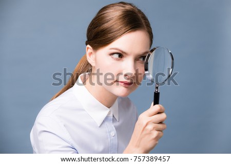 Young woman looking at something with magnifying glass.