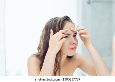 Young woman  looking and squeeze  acne on a face in front of the mirror. Ugly problem skin girl, teen girl having pimples. Skin care. Beauty