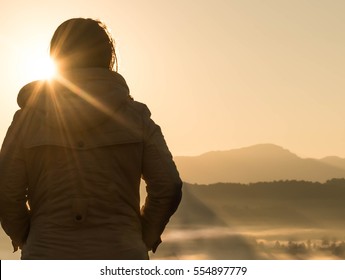 A Young Woman Is Looking At The Sun Rise Over The Mountain.