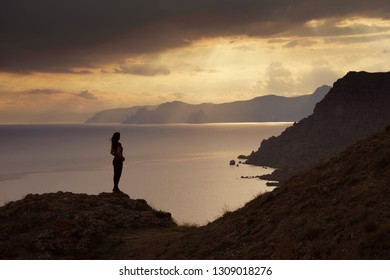 Young woman looking at sunset coast.