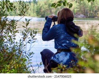 Young woman looking through binoculars at birds on the lake. Birdwatching, zoology, ecology. Research in nature, observation of animals Ornithology autumn bird migration selective focus, soft focus.  - Shutterstock ID 2147006025