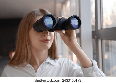 Young woman looking through binoculars in window at home, closeup - Powered by Shutterstock