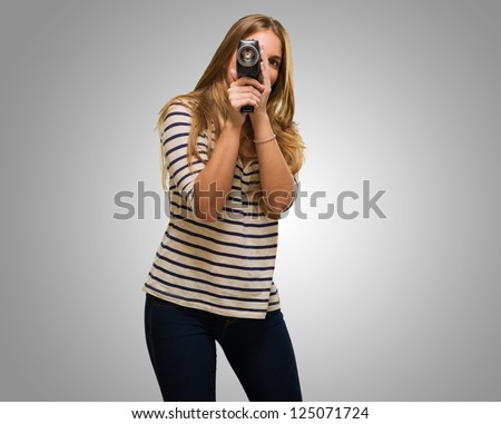Young Woman Looking Through A Camera against a grey background