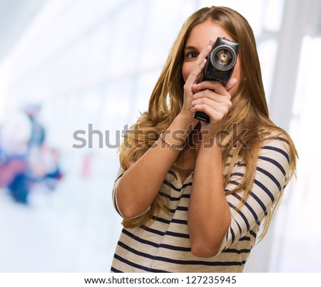 Young Woman Looking Through A Camera against an abstract background