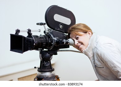 Young Woman Looking Through Old Movie Camera.