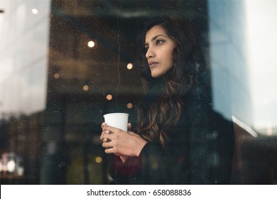 Young Woman Looking Through Rainy Window