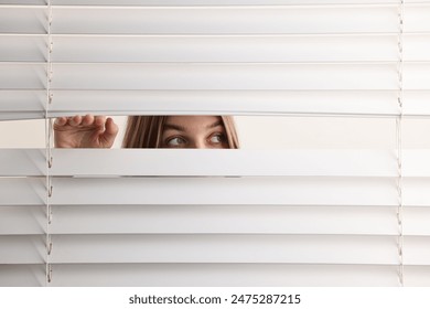 Young woman looking through window blinds on white background, space for text - Powered by Shutterstock