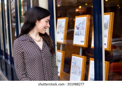 Young Woman Looking In The Window Of An Estate Agent