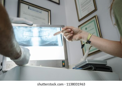 Young woman looking at the x-ray of her mouth while the dentist explains to her at the dental clinic. 