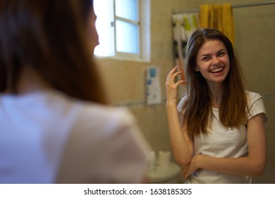 young woman looks in the mirror in a white t-shirt - Shutterstock ID 1638185305