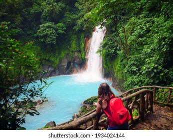 Young woman looks out over a picturesque rain forest waterfall in Costa Rica.
