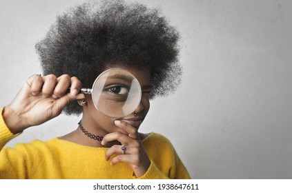young woman looks through a magnifying glass