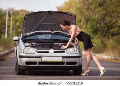 Young Woman Looks Under The Hood Of His Car, Which Was Broken. 