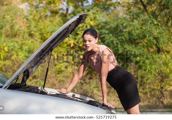 Young woman looks under the hood of his car, which broke
down 