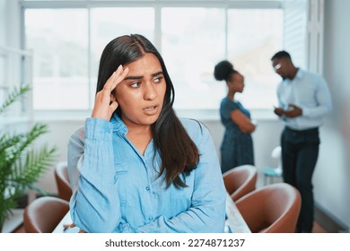 Young woman looks upset while colleagues talk behind her back, office drama - Shutterstock ID 2274871237