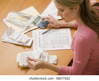 A Young Woman Looks Upset While Sorting Through Her Old Receipts.  Horizontal Shot.