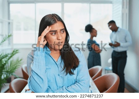 Young woman looks upset while colleagues talk behind her back, office drama
