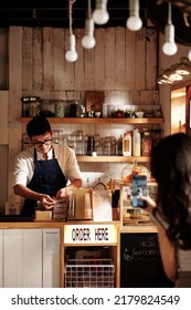 Young Woman In Love Secretly Filming Barista Working At Coffeeshop Counter