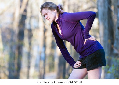 Young Woman With Lower Back Pain While Running Exercising On Nature Trail Outdoors