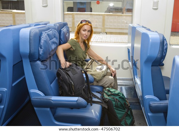 Young woman with\
luggage in car of train