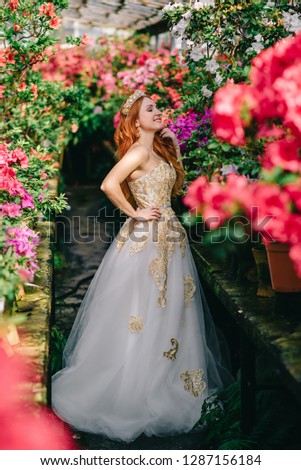 young woman in luxurious dress standing in flowered garden
