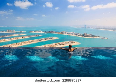 Young woman in luxury infinity pool over palm Jumeirah islands and dubai city skyline
