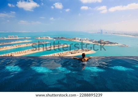 Young woman in luxury infinity pool over palm Jumeirah islands and dubai city skyline