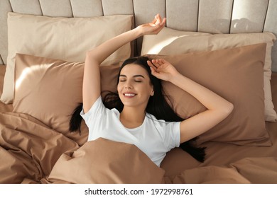 Young woman lying in bed with brown linens at home, above view - Powered by Shutterstock