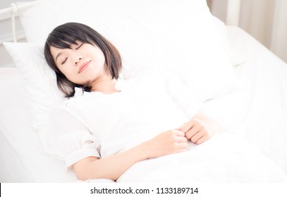 Young woman lying in bed at home in the bedroom - Shutterstock ID 1133189714