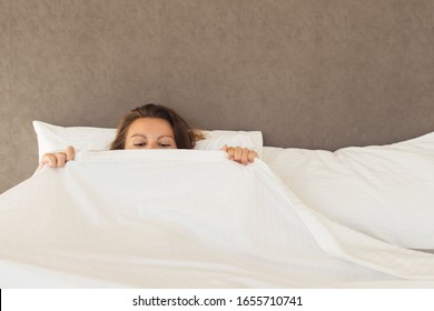 A Young Woman Lying In Bed And Looking On Herself Under Sheet. Concept 