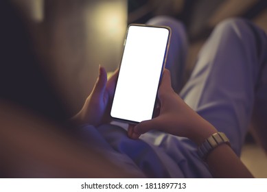 Young woman lying in bed playing the phone in the house before going to bed - Powered by Shutterstock