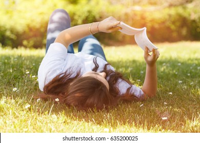 jeune femme allongée sur l'herbe lisant un livre