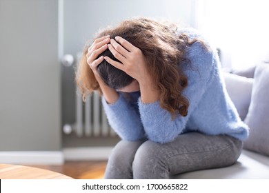 Young woman lying at home in living room sitting on sofa. She feeling sad and worried suffering depression in mental health. Problems and broken heart concept. - Powered by Shutterstock
