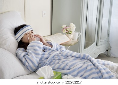 Young Woman Lying On Bed With Common Cold