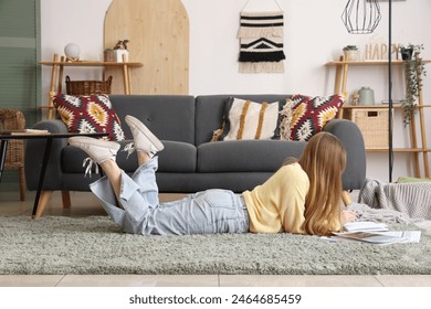 Young woman lying on floor and reading magazines in living room - Powered by Shutterstock